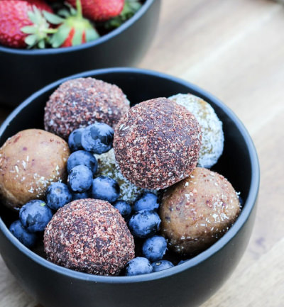 An image of a bowl of protein balls and blueberries