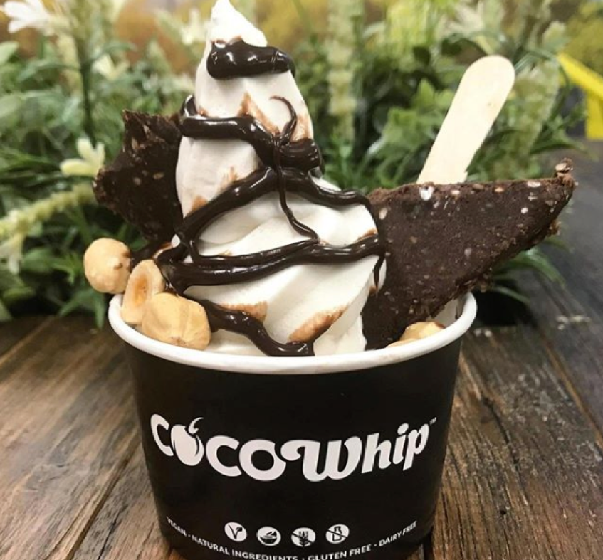 Cup of Cocowhip with vegan brownie, nuts and chocolate sauce
